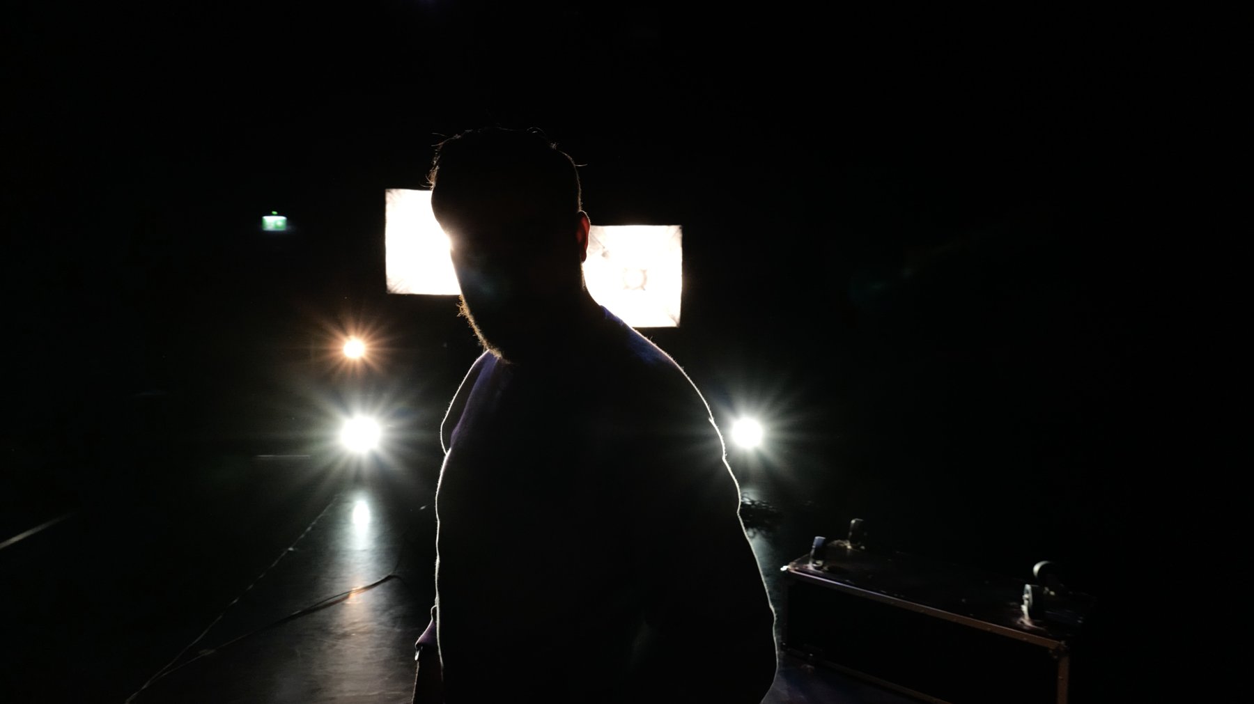 Backlit silhouette of a performer against bright softbox lights
