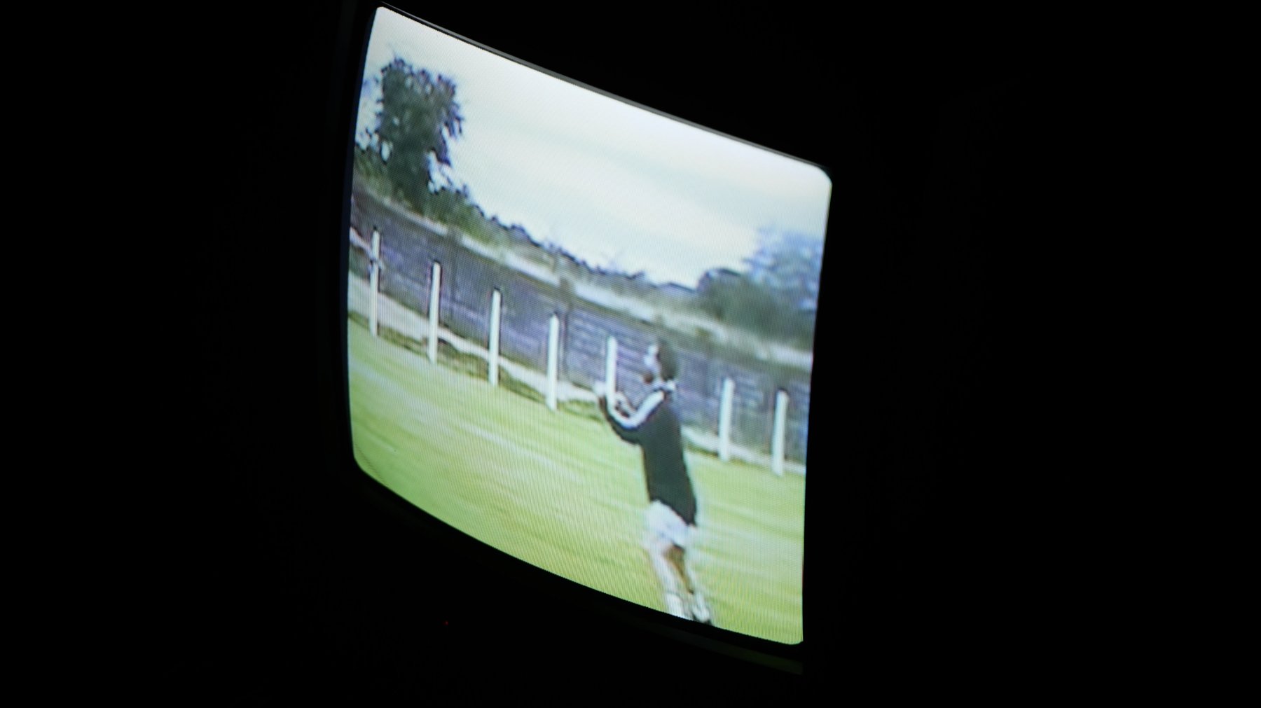 An old television showing archive footage of a person on a grass field