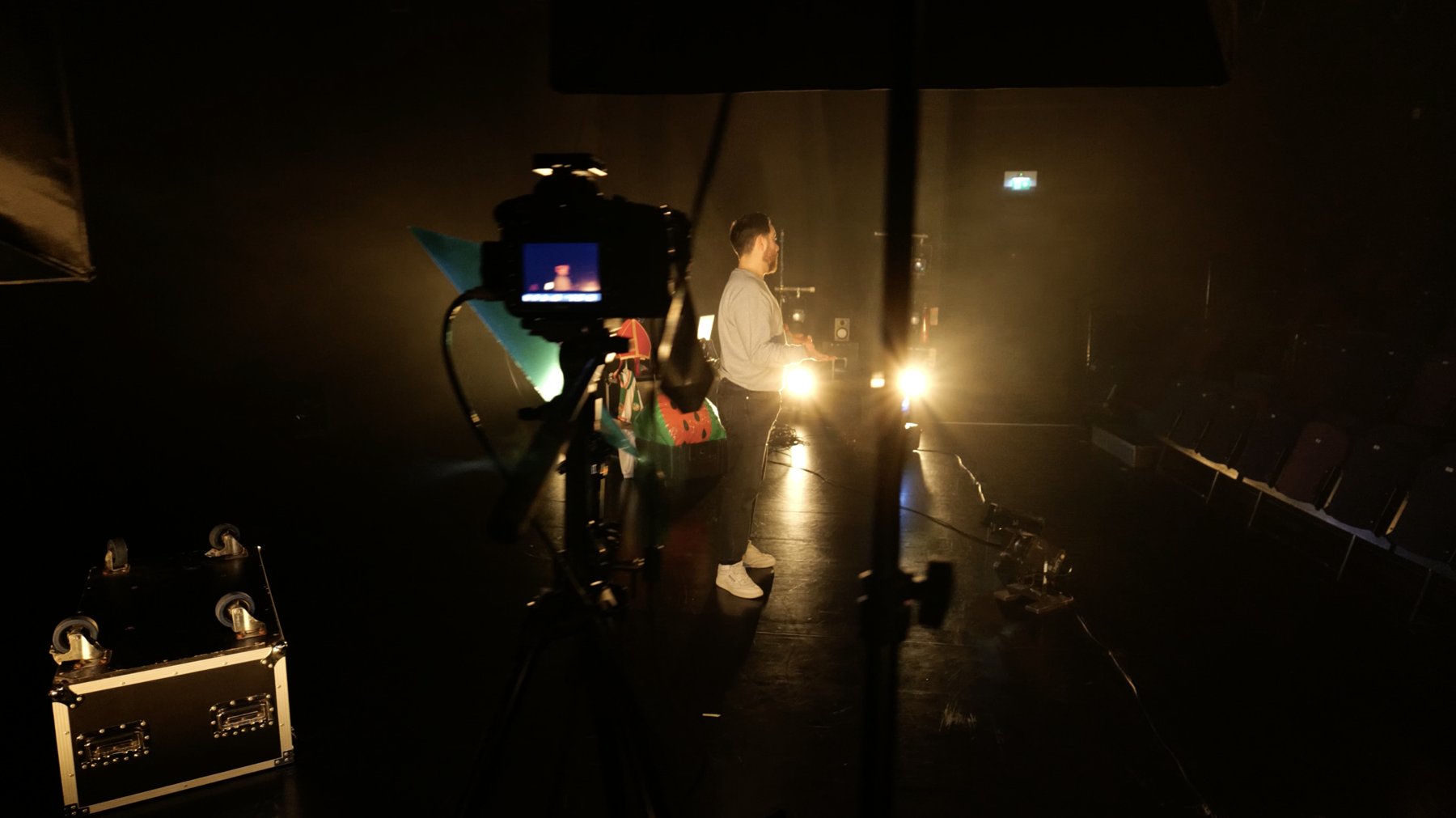 Behind the scenes: a camera on a tripod films the performer on stage